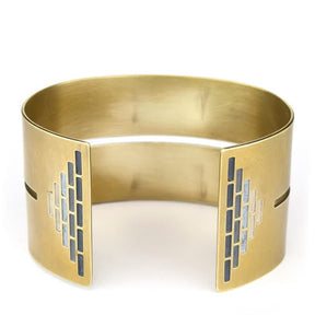 Wide, bold, brass cuff bracelet in the Portland colorway, with a cutout slit that runs through the center of the cuff and stops just short of a pyramid of grayscale paint on either end. Hand-crafted in Portland, Oregon. 