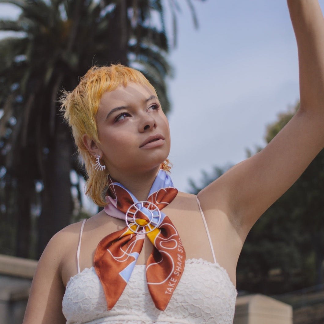 Model wears silver scarf bolo with a multi colored scarf. The Scarf Bolo is designed and handmade by Take Shape Studio in Berkley,  California.