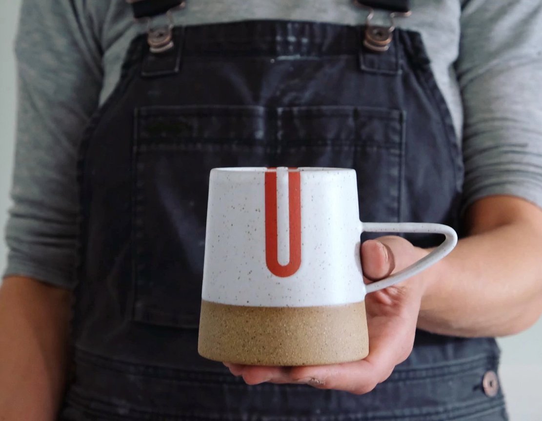 Handle mug with a white speckled and natural clay finish along with red detailing. The Tucker Mug with Red Detail is designed and handmade by Wolf Ceramics in Hood River, Oregon.