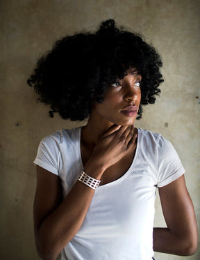 Modern, adjustable cuff of silver-plated brass, modeled after the Edmund Pettus Bridge in Selma, Alabama, worn on a model with curly black hair and a white, scoop-neck t-shirt.