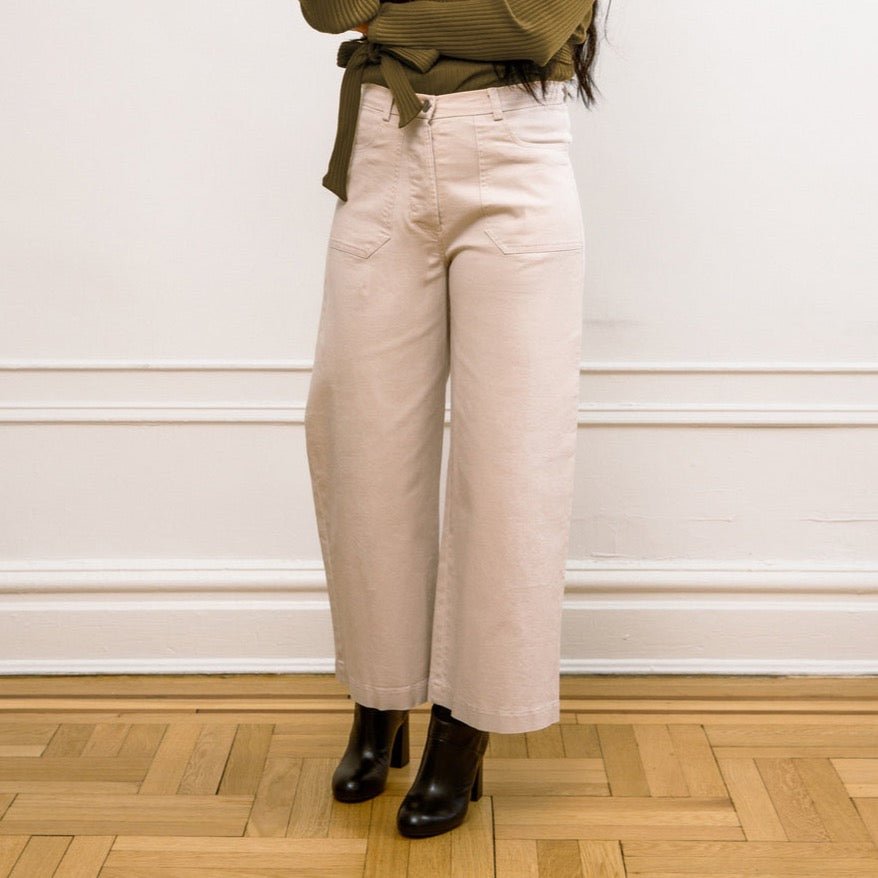 A model wears a high waisted wide leg cropped jean in an off-white color. The Simone Jean in Sand is designed by Loup and made in New York City, USA.