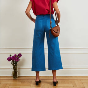 A model shows the backside of a wide leg cropped light blue pant. The Simone Jean in Azure is designed by Loup and made in New York City, USA.