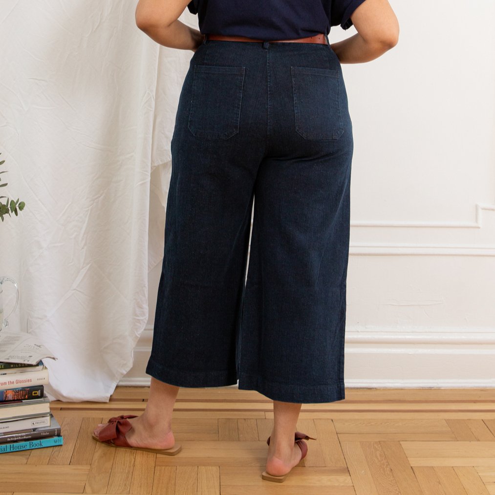 A model shows the backside of a high waisted wide leg cropped jean in a dark blue denim. The Simone Jean in Dark Indigo is designed by Loup and made in New York City, USA.