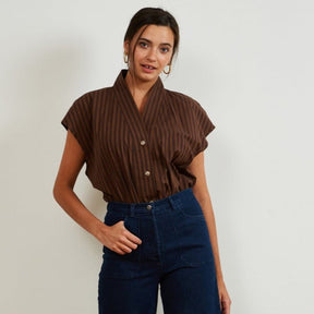 A short sleeve tunic button up in brown stripes. Model has shirt tucked into denim jeans. The Sienna Top in brown Stripe is designed by Loup and made in New York City.