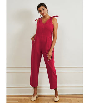 Model wears a bright pink colored jumpsuit with a V-neckline and tie up shoulder straps. The Slate Overalls in Rose are designed by Loup and made in New York City, USA.