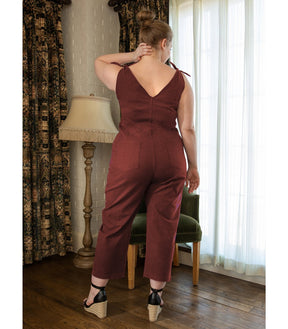 Model shows the back side of a rusty red colored jumpsuit with a V-neckline and tie up shoulder straps. The Slate Overalls in Terracotta are designed by Loup and made in New York City, USA.