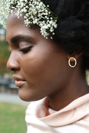 A model wears a 22 kt gold plated stud earring. The Small Boulder Earrings are designed and handcrafted by Lingua Nigra in Chicago, Illinois.