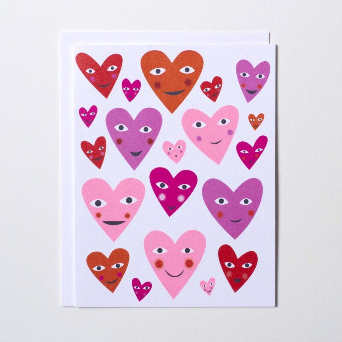 White card with bright pink, red and purple smiley face hearts. Made with recycled paper by Banquet Atelier in Vancouver, British Columbia, Canada.