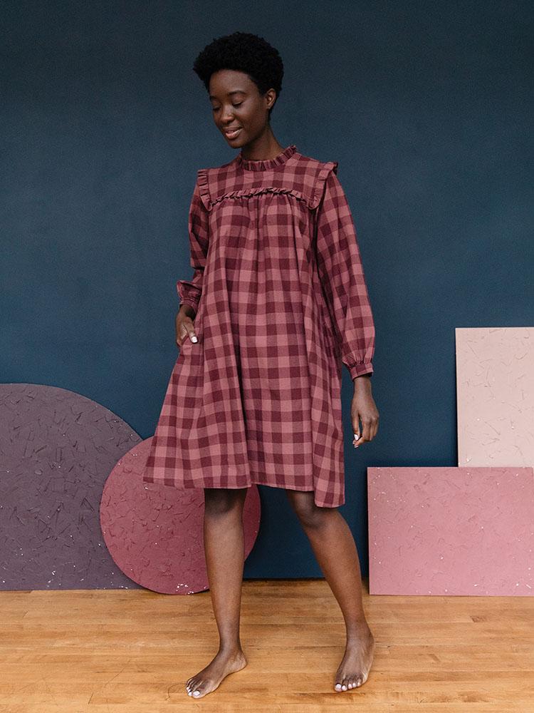 Long sleeve mini dress with ruffles, waist tie and pockets in a plum colored gingham pattern fabric. Designed by Mata Traders and made in Nepal.