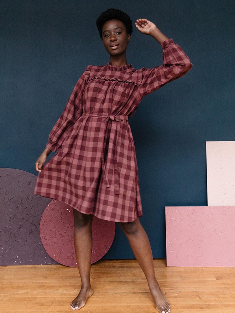 Long sleeve mini dress with ruffles, waist tie and pockets in a plum colored gingham pattern fabric. Designed by Mata Traders and made in Nepal.