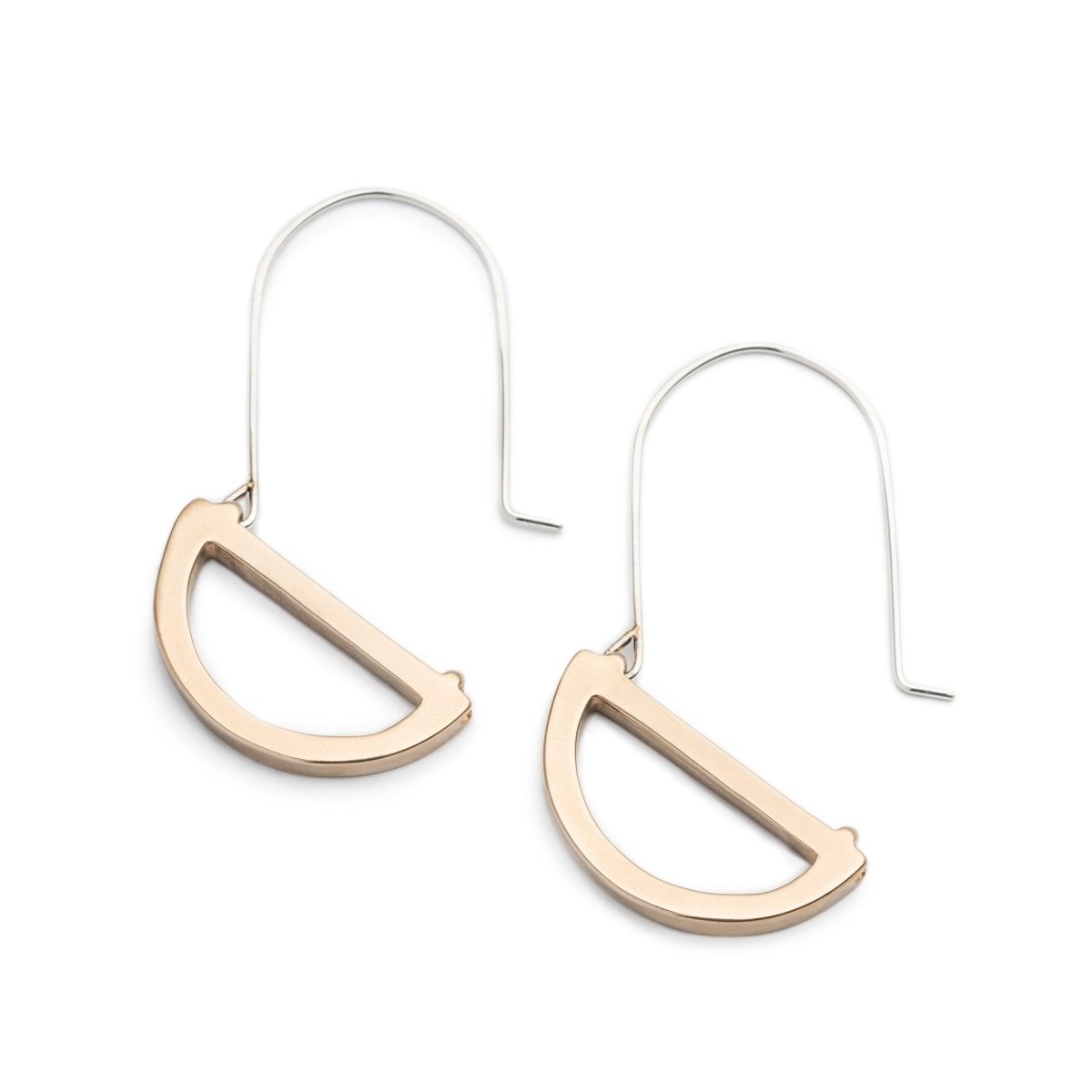 Modern, polished, cast bronze semicircle pendants hanging below long, hand-formed, sterling silver hoops. Hand-crafted in Portland, Oregon.