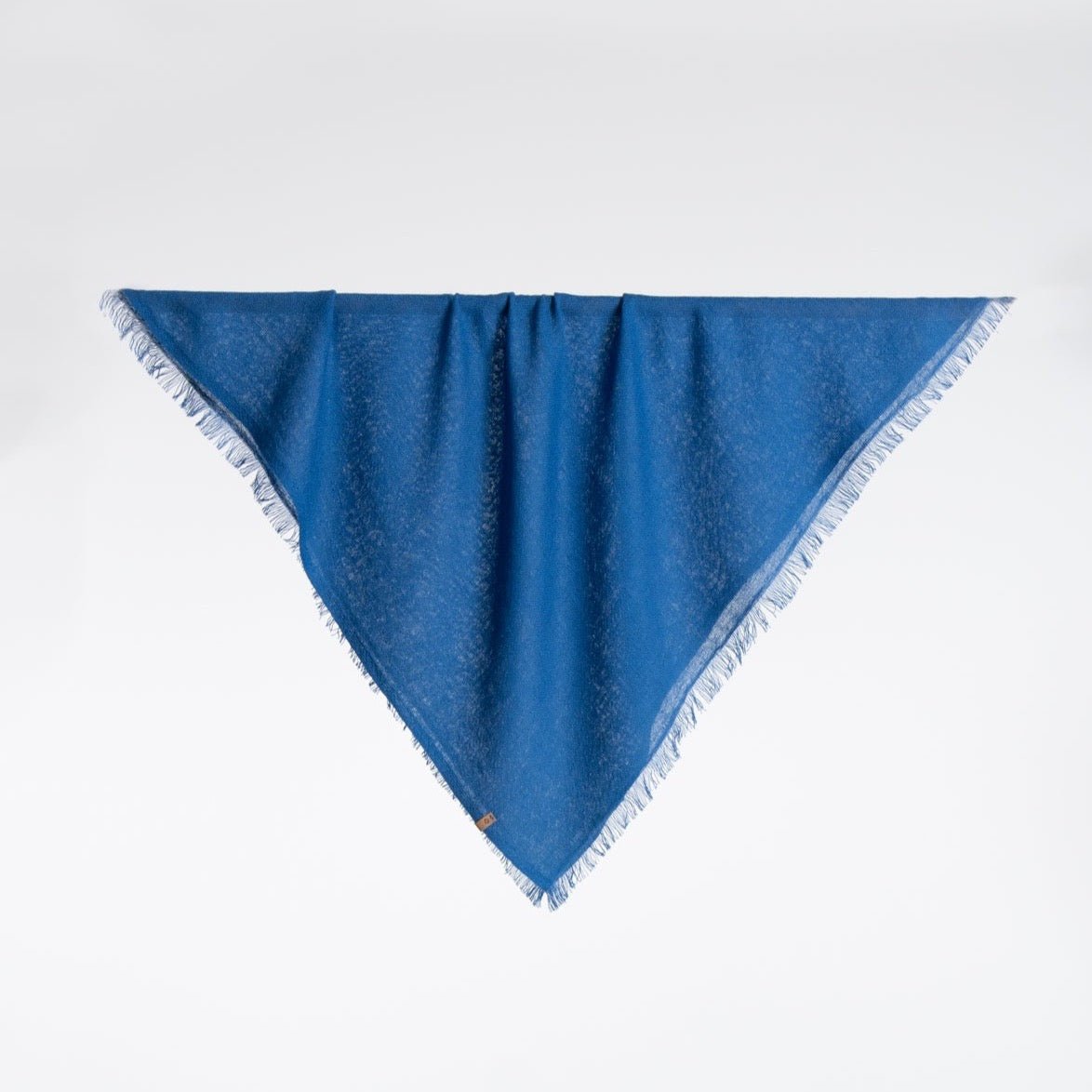 A square scarf made of 100% Merino wool in a deep blue color. The Merino Square Woven Scarf in Ocean Blue is designed by Dinadi and handcrafted in Nepal.