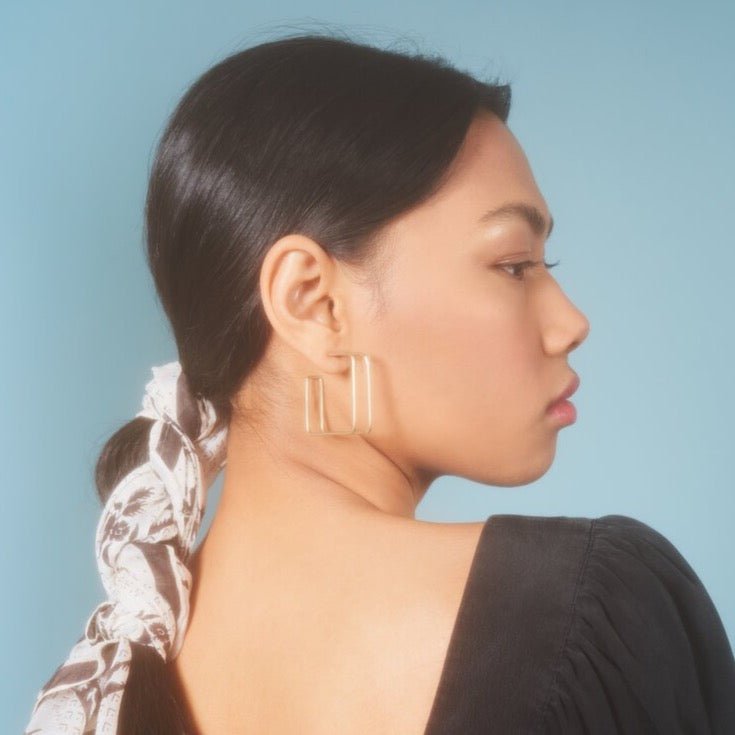 Square Caged Hoops in size large. Worn on a model with black hair. Designed and handcrafted by Natalie Joy in Portland, Oregon.