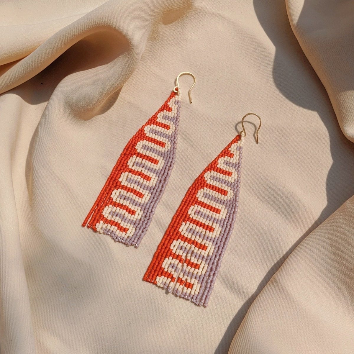 Woven red, white and pastel purple beaded fringe earrings. Designed and handmade by Take Shape studio in Berkeley, California.