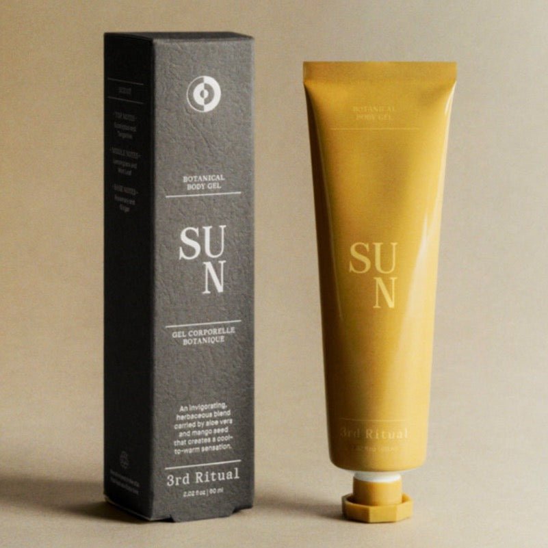 A yellow tube of gel stands next to a grey rectangular box. The Sun Botanical Body Lotion is developed and formulated by 3rd Ritual in New York City, NY.