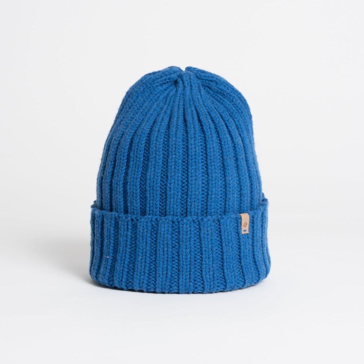 A bright blue cuffed hat with thick ribbed design and decrease detail at the top. The Merino Thick Rib Hat in Ocean Blue is designed by Dinadi and hand knitted in Kathmandu, Nepal.
