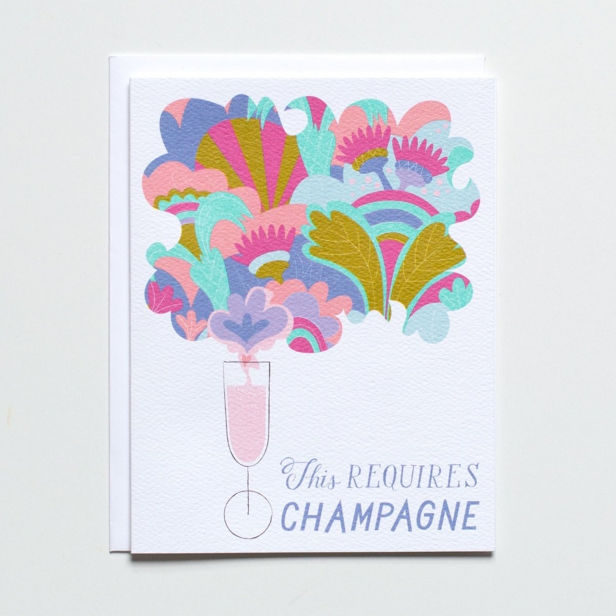 White greeting card with an illustration of a champagne glass emitting whimsical pink, green, teal, and blue illustrations. Front of card reads: "THIS REQUIRES CHAMPAGNE." Made with recycled paper by Banquet Atelier in Vancouver, British Columbia, Canada.