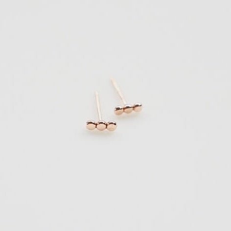 A gold fill stud earring in a three dot pattern. The three Dot Studs are designed and handcrafted by Deivi Arts Collective in Vancouver, Canada.