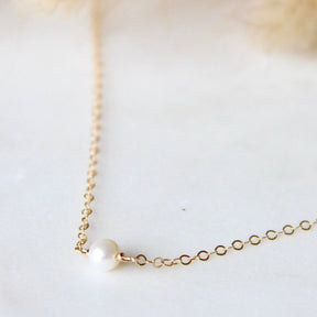 A dainty chain necklace with a tiny freshwater pearl focal piece. The Tiny Freshwater Pearl Necklace is handcrafted by Hello Adorn in Eau Claire, WI.