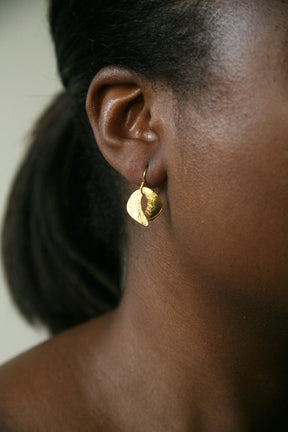 Two crescent shapes come together to form a circular dangle style earring. Made in cast brass and plated in 22kt gold. The Tiny Sculptured Earrings are designed by Lingua Nigra and handcrafted in Chicago, Illinois.