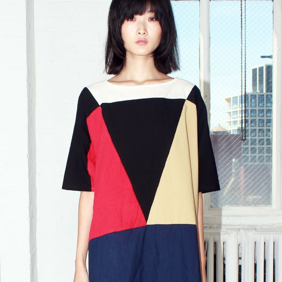 Red, blue, black, white and pale yellow colored tunic style dress with color-blocked triangle design. Designed and sewn by Uzi in Brooklyn, New York.