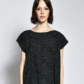 a model wears a short sleeve back tunic with white speckle design. The Tunic in Black Speckle is designed and sewn by UZI NYC in Brooklyn, New York.
