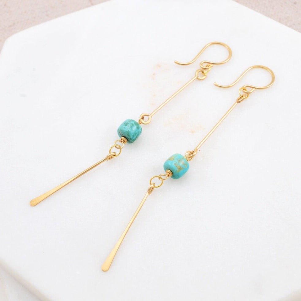 Smooth New Mexican turquoise barrels have been wrapped in gold and are suspended below a gold fill bar and above a hammered gold fill paddle. Designed and handmade by Amy Olson in Portland, Oregon.