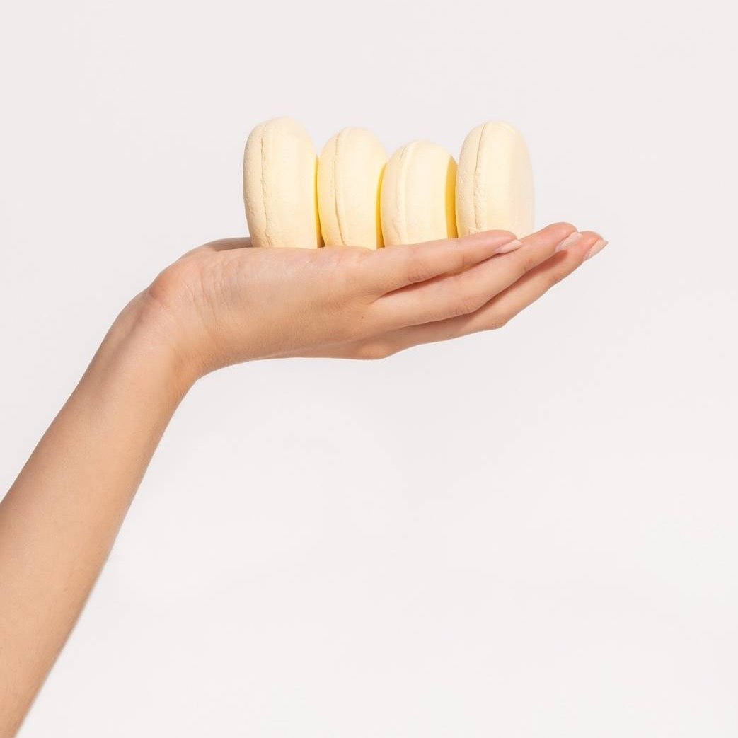 A model holds four shower steamer disks. The Aromatherapy Shower Steamers in Uplift are formulated by Klei Beauty and manufactured in New Jersey, USA.