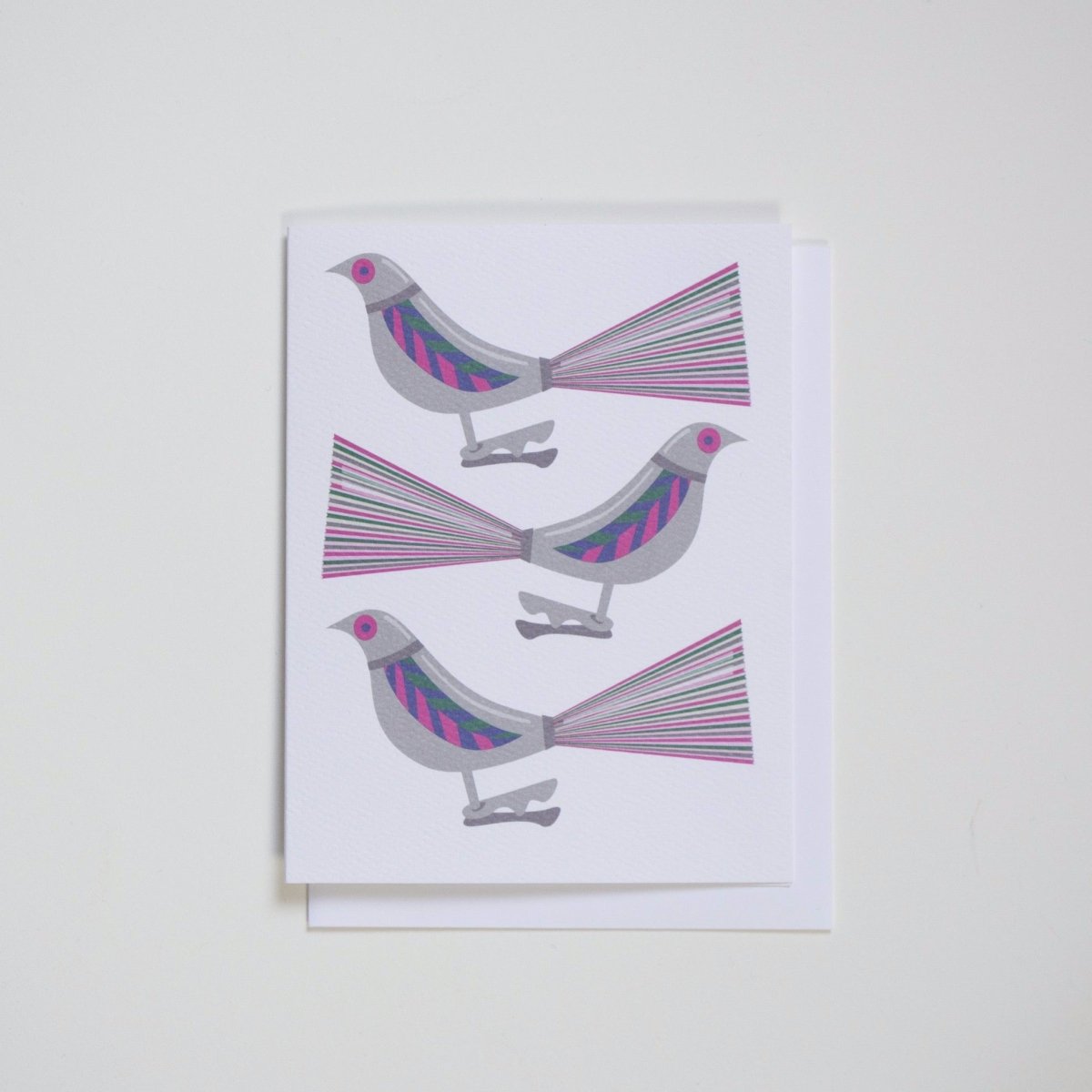 Three silver, pink, green and blue vintage style clip on bird ornaments against a white background. Made with recycled paper by Banquet Atelier in Vancouver, British Columbia, Canada.