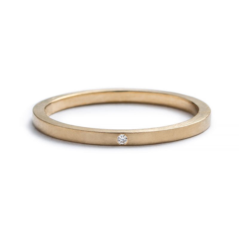 Thin, 14k yellow gold stacking band with a matte finish, and a tiny, round, flush-set white diamond. Hand-crafted in Portland, Oregon. 