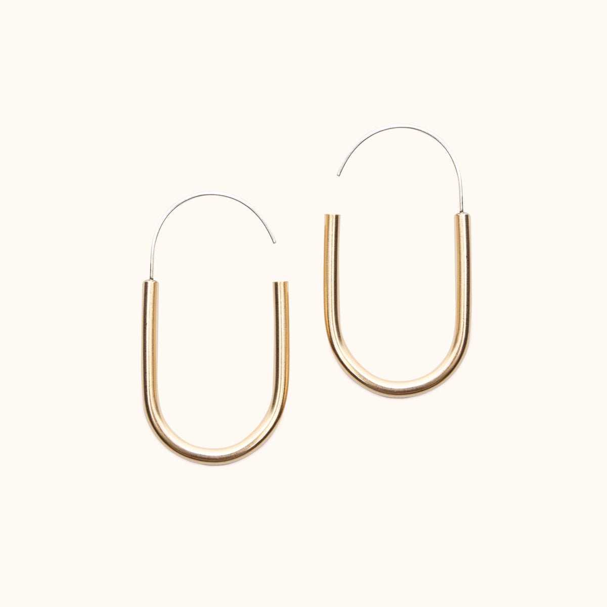 A small brass U-shaped earring with an arched sterling silver ear wire that leaves a slight opening. Designed and handcrafted in Portland, Oregon.