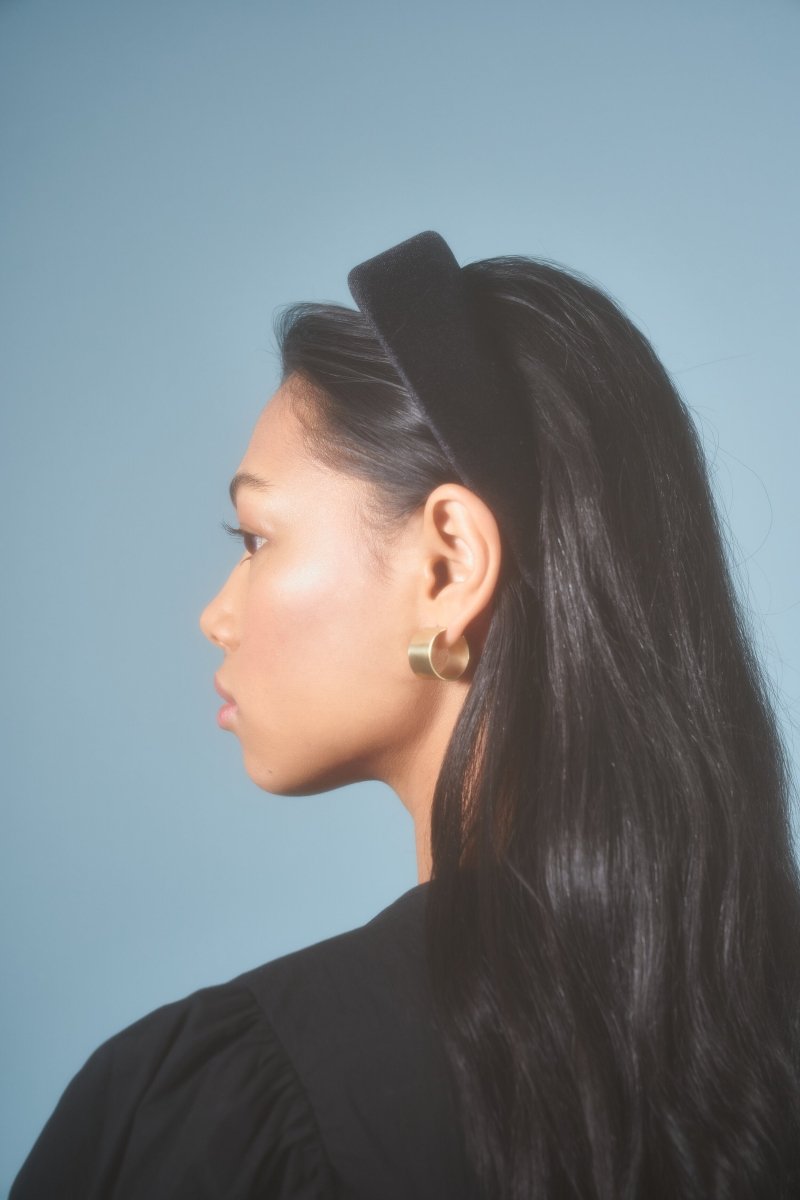 Model with long black hair wears small brass Wide Circle Hoops. Earrings made by Natalie Joy in Portland, Oregon.