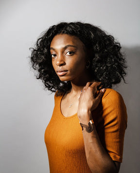 The bronze Willamette cuff, bronze betsy & iya Forti ring, and sterling silver betsy & iya Amare necklace, styled together on a model wearing an ochre dress.