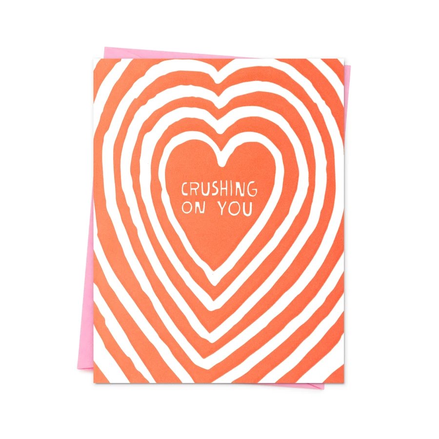 Red and white greeting card with a pink envelope. The center of the card reads: " CRUSHING ON YOU," and is blank inside. The Crushing on You Card from Ashkahn is designed in Los Angeles and printed in Portland.