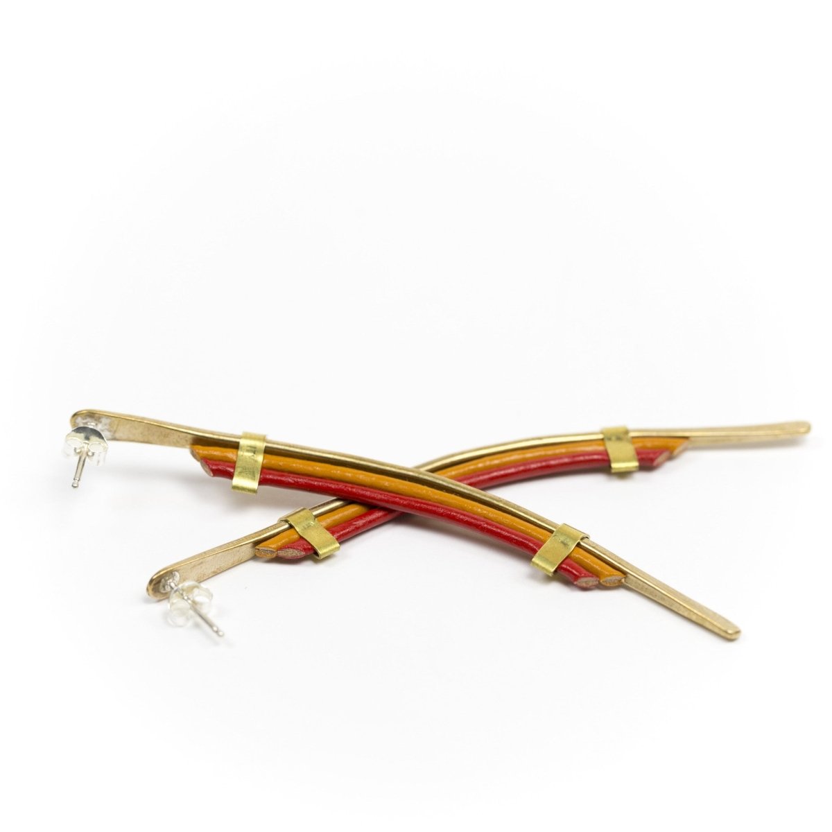 Long spear shaped gold earrings with sterling silver posts and red leather accents.