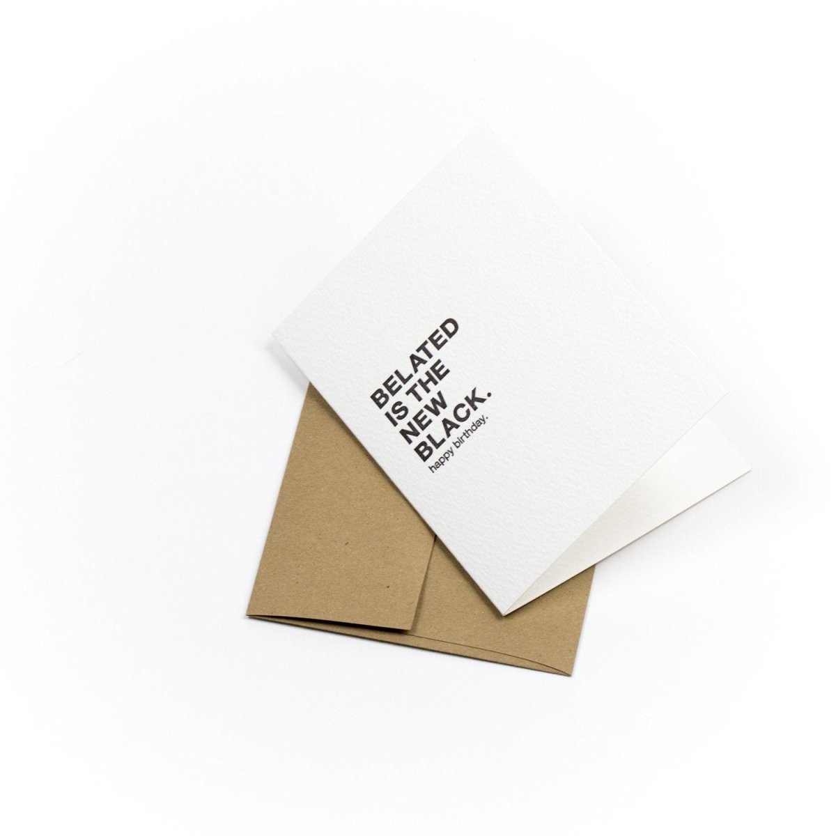 Kraft card with black text that reads: "BELATED IS THE NEW BLACK. HAPPY BIRTHDAY." Designed and made by Sapling Press in Pittsburgh, PA.