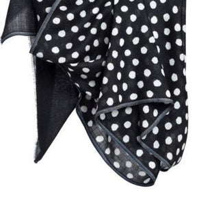 Black scarf with white dots hangs in the air. The Maya Dot Scarf in Black is from Bloom & Give.