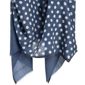 Blue scarf with white dots hangs in the air. The Maya Dot Scarf in Blue is from Bloom & Give.