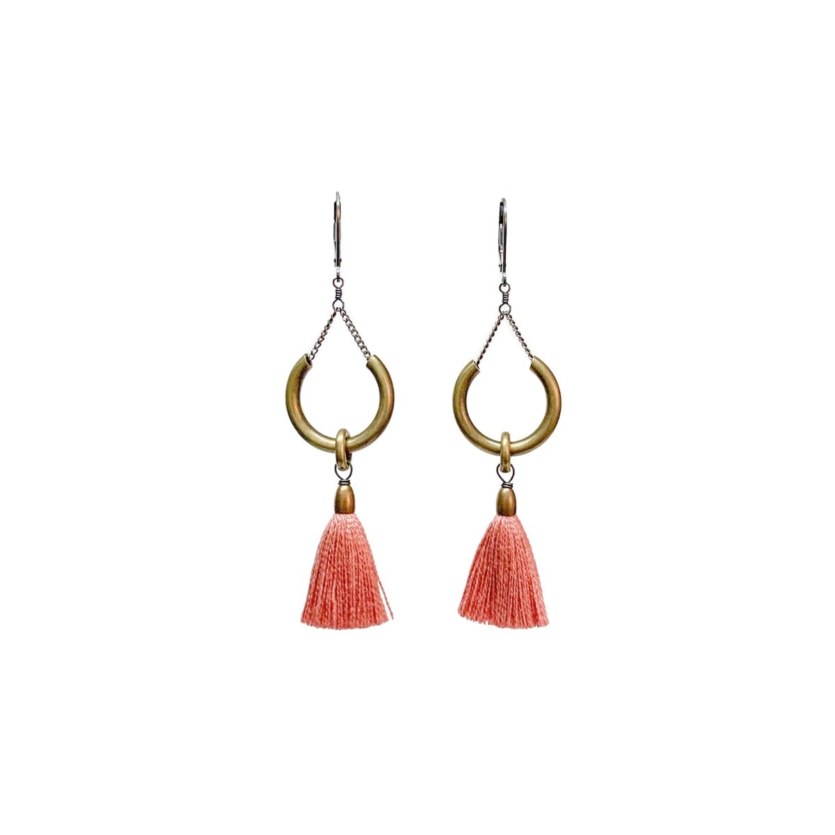 A pair of earrings with silver clasps, a brass ring and blush pink tassels. The Duster Earrings in Shell are from Portland designer Emily Bixler of BOET.
