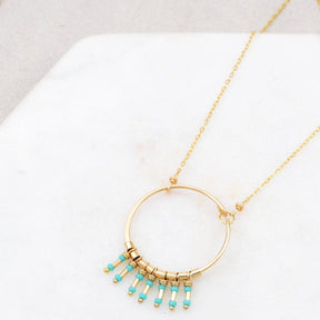 A gold fill hammered circular focal piece with turquoise and gold-fill bead fringe. The Clarice Necklace in Turquoise is designed and handcrafted by Amy Olson in Portland, Oregon.