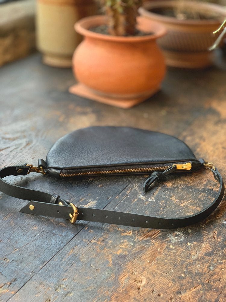 Black leather fanny pack with adjustable leather strap. Features brass hardware and can fully detach from bag. Crafted in Portland, Oregon by Frankie & Coco.