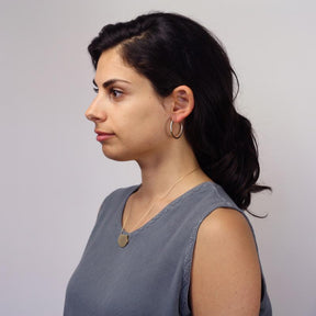 Minimalist, lightweight, and mixed-metal betsy & iya Small Koa Hoop Earrings, pictured on a model wearing a gray tank top and 14k gold-plated Novi necklace.