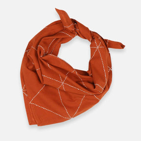 A rust colored bandana with white stitching. The Graph Bandana in Rust is designed by Anchal in Louisville, Kentucky and handmade in Ajmer, India.
