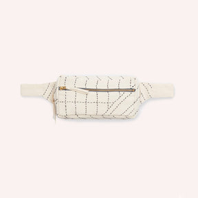 An off white crossbody bag with black stitched detail. The Crossbody Belt Bag in Bone is designed by Anchal in Louisville, KY and handmade in Ajmer, India.
