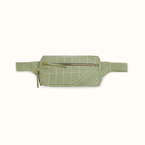 A light green crossbody bag with white stitched detail. The Crossbody Belt Bag in Sage is designed by Anchal in Louisville, KY and handmade in Ajmer, India