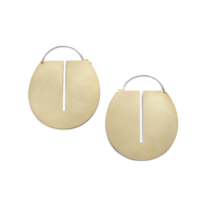 Large, round, brushed brass disc hoop earrings with a thin, rectangular cutout running down the center of the discs, and short, sterling silver earring wires that latch to the back of the discs. Hand-crafted in Portland, Oregon. 