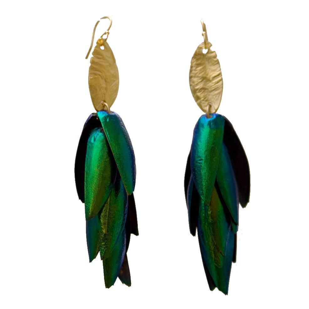 Closeup of brass earrings with blue and green beetle wings. The etched brass is connected to vermeil earwires. The Body that Remains earrings are from designer Lingua Nigra.