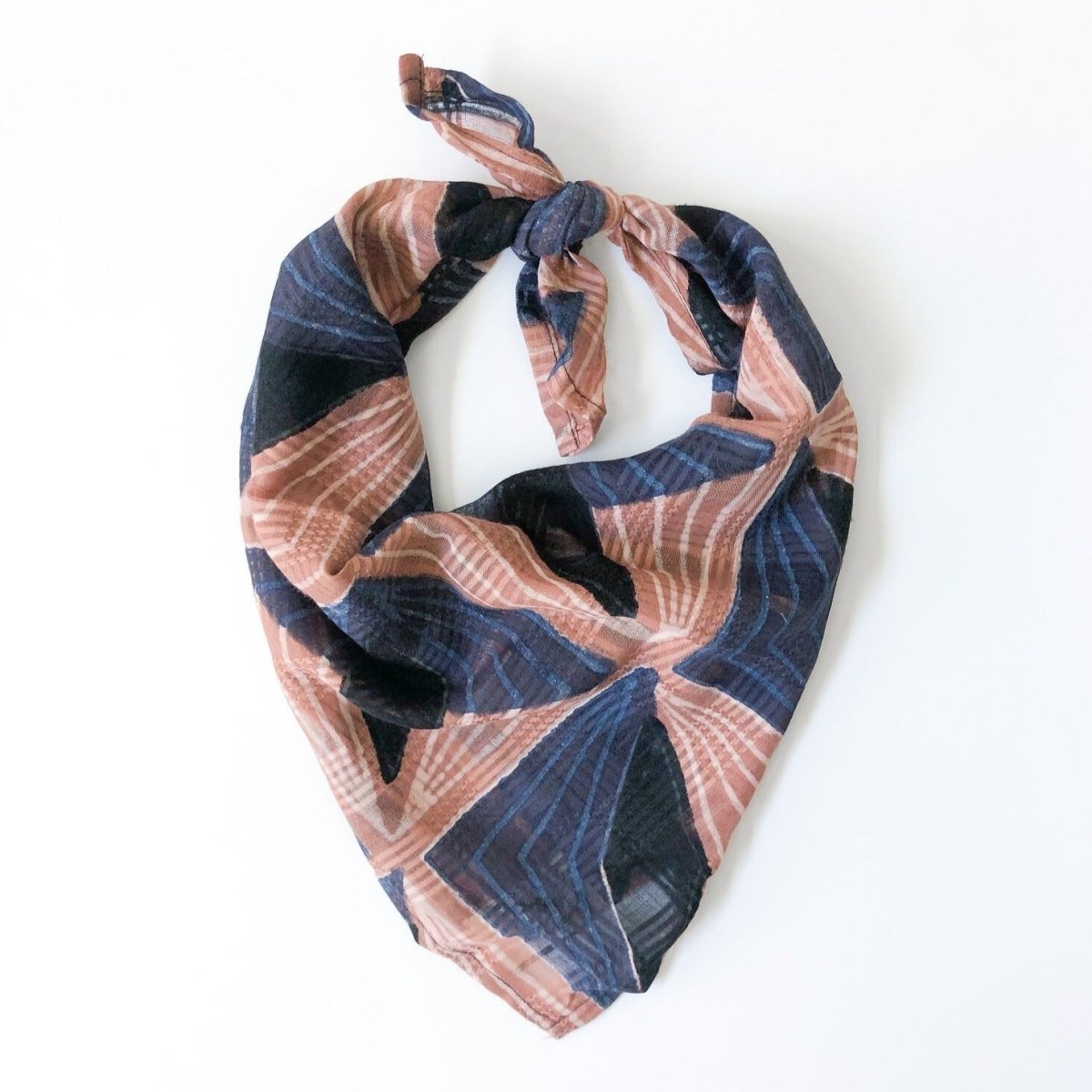 A blue and pink bandana, folded over and tied in a knot. Block printed by hand, the Lola Bandana from Maelu is designed in Portland, Oregon and handmade in India.