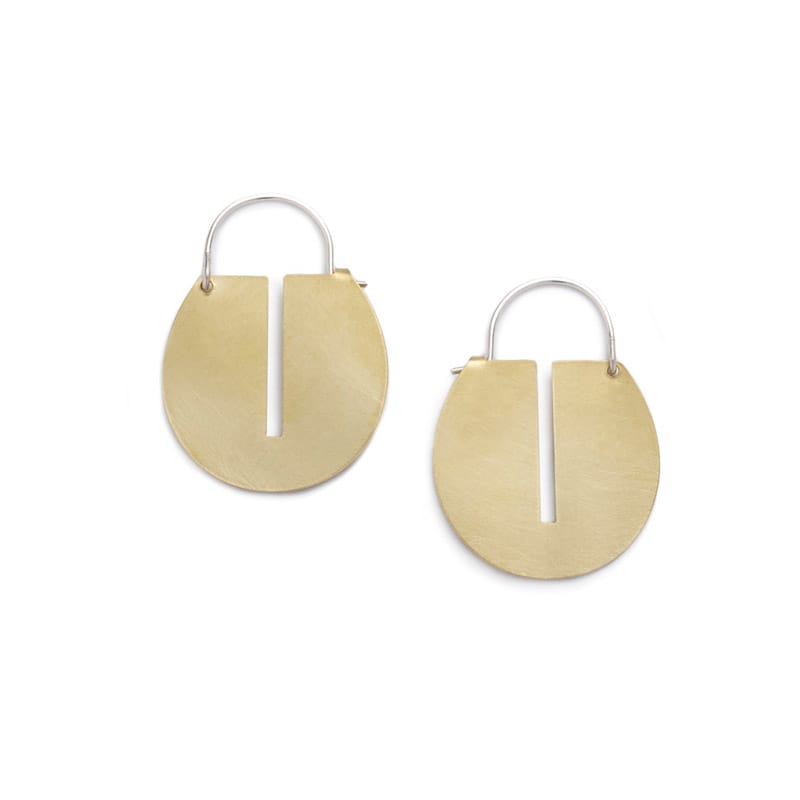Small, round, brushed brass disc hoop earrings with a thin, rectangular cutout running down the center of the discs, and short, sterling silver earring wires that latch to the back of the discs. Hand-crafted in Portland, Oregon.