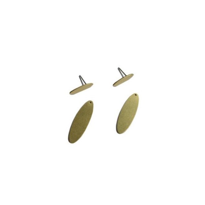 A pair of disassembled oval brass earrings against a white background. The Oval Ear Jacket earrings are from Portland designer Natalie Joy.